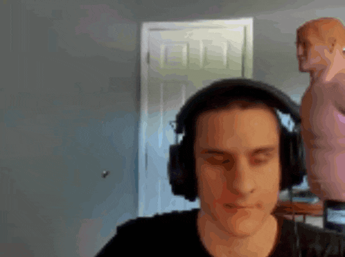 a man wearing headphones with his eyes closed in front of a mannequin