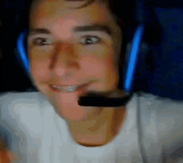 a man wearing headphones and a microphone is smiling while looking at the camera .