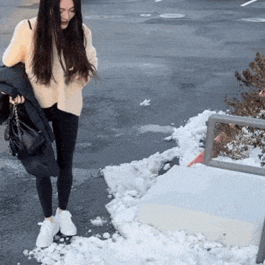 a woman wearing a white sweater and black leggings stands in the snow
