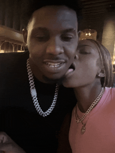 a woman kisses a man on the cheek who is wearing a black shirt