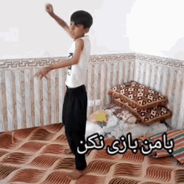 a young boy is standing in a room with arabic writing on the bottom
