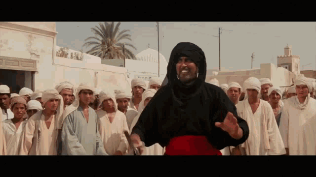 a man in a black robe stands in front of a crowd