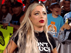a woman wearing a t-shirt that says " do n't touch " is standing in front of a crowd