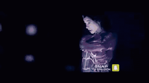 a woman is standing in a dark room holding a cell phone in her hands .