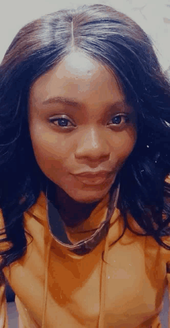 a close up of a woman 's face wearing a yellow sweatshirt