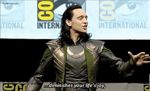a man in a loki costume stands in front of a sign that says comic con