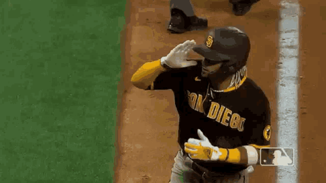 a baseball player is wearing a san diego jersey and gloves while standing on the field .