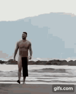 a shirtless man is walking on the beach without a shirt .
