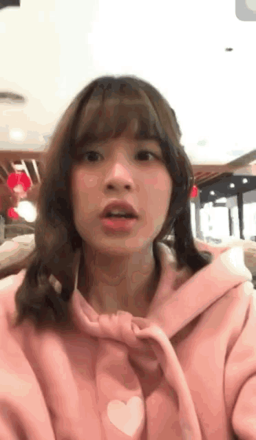 the girl is wearing a pink hoodie with a heart on it and pigtails .