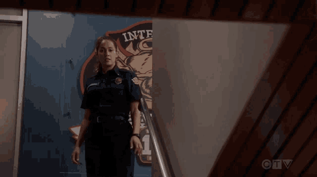 a woman in a police uniform stands in front of a wall that says " inter "