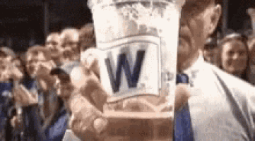 a man is holding a cup of iced tea with a w on it in front of a crowd of people .