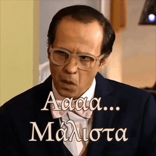 a man wearing glasses and a suit has the words " aaa ... maliota " written on the bottom