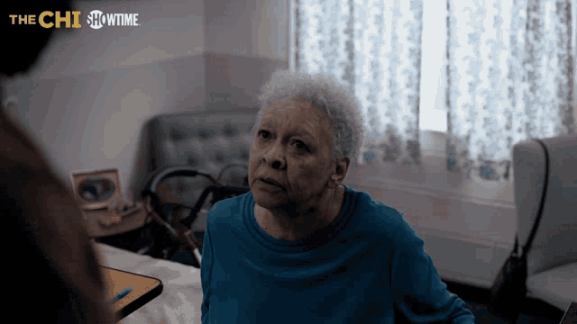 a woman in a blue shirt is sitting in a room with the showtime logo on the bottom