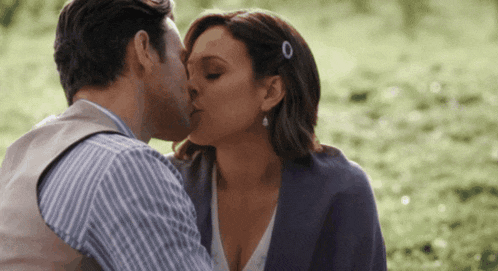 a man and woman are kissing in a field