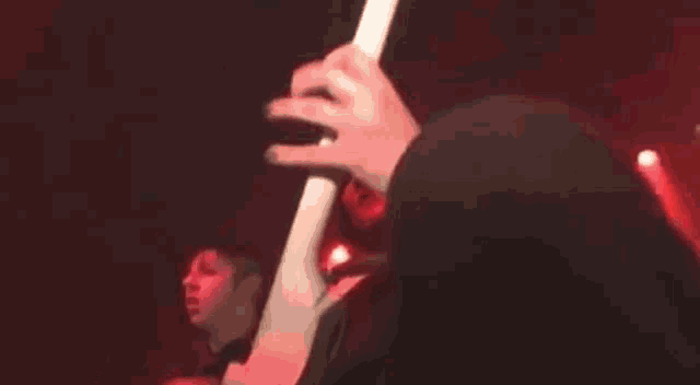 a man is playing a guitar on a stage in a dark room with red lights .