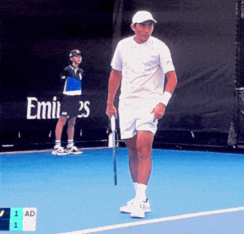 a man holding a tennis racquet on a tennis court in front of an emirates banner