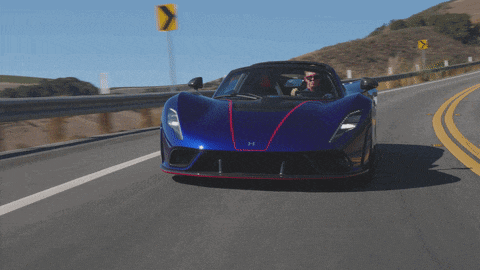 a man driving a blue sports car on a highway