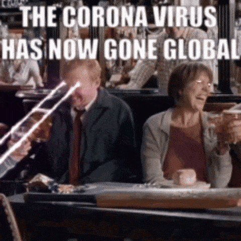 a group of people are sitting at a table with glasses of beer and a sign that says the corona virus has now gone global .