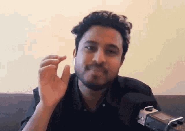 a man with a beard is sitting in front of a microphone and holding something in his hand