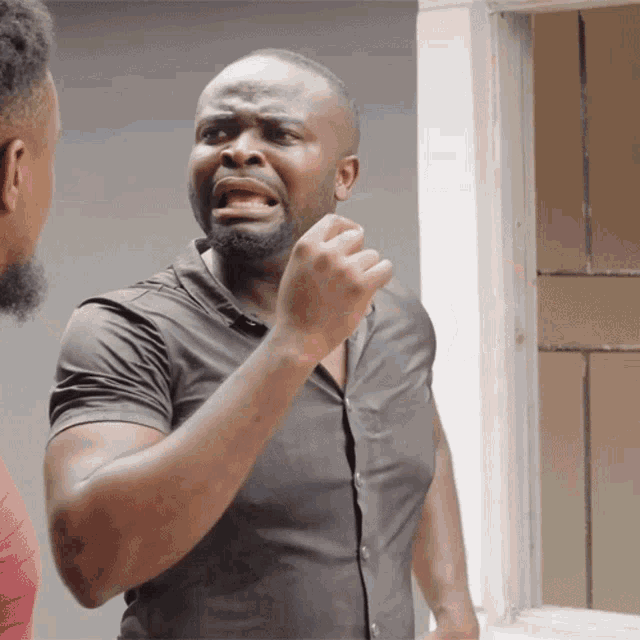 a man in a black shirt is making a funny face while another man in a red shirt looks on