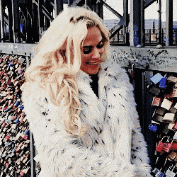 a woman in a white fur coat is smiling
