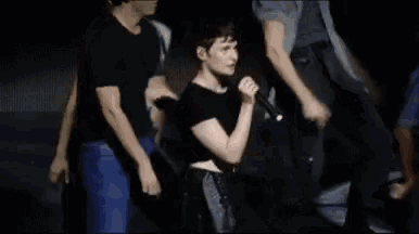 a group of people are standing around a man in a black shirt .