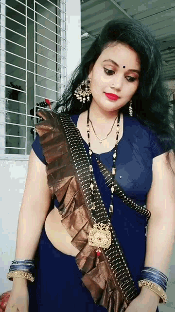 a woman is wearing a blue top and a brown ruffled saree .