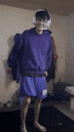 a man wearing a purple hoodie and purple shorts is standing in a room with headphones on .