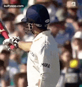 a cricket player wearing a helmet and holding a bat in his hand .