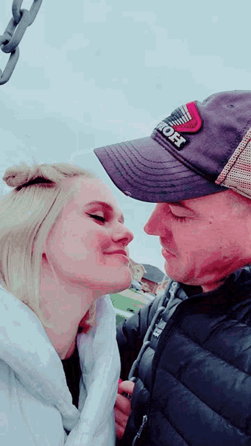 a man wearing a hat that says " off " kisses a woman