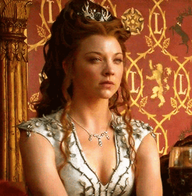 a woman with a crown on her head is wearing a necklace with the letter i on it