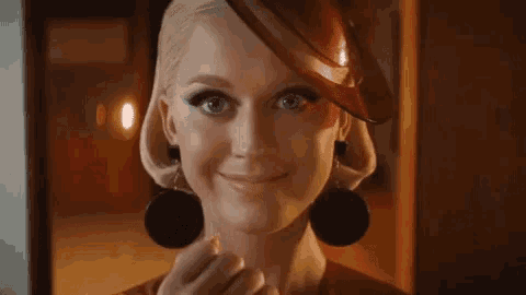 a close up of a woman wearing a red hat and earrings .