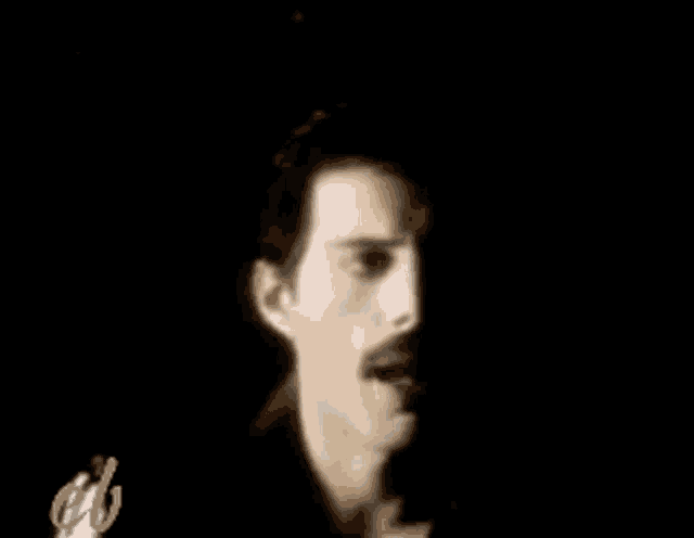 a close up of a man 's face with a mustache in a black background .