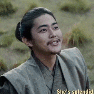 a man with a beard and a ponytail is smiling while wearing a kimono .