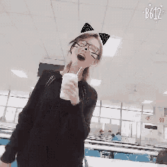 a woman wearing cat ears and glasses is holding a cup of milkshake