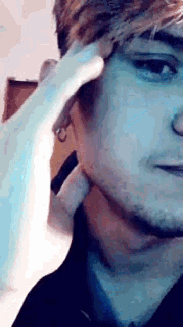 a close up of a man 's face with a hand holding his ear .