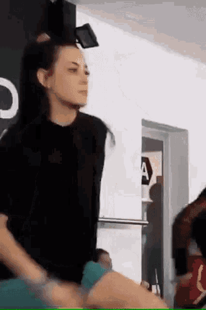 a woman in a black shirt is dancing in a room with a sign that says a .