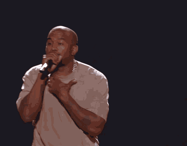 a man singing into a microphone while wearing a tan shirt