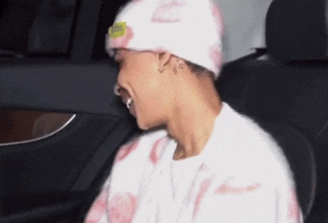 a man wearing a pink hat and a white shirt is sitting in the back seat of a car
