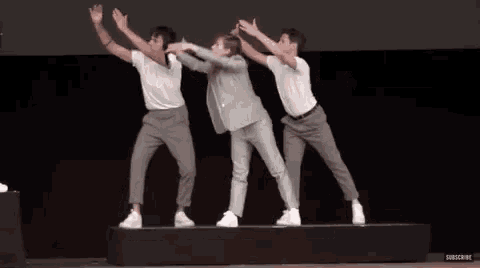 a group of men are dancing on a stage with their hands in the air .