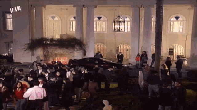 a large group of people are gathered in front of a building that says viva on it