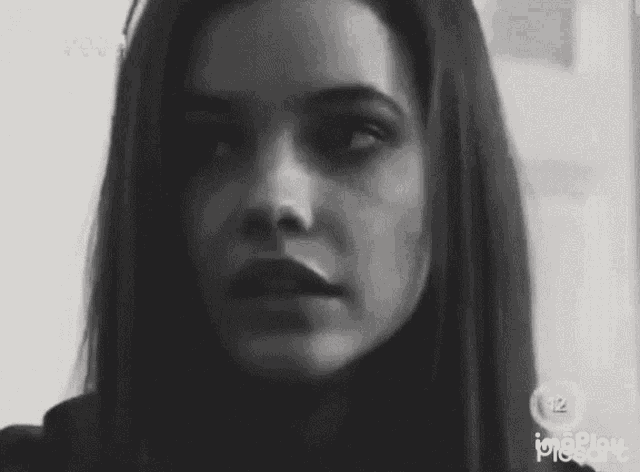 a woman 's face is shown in a black and white photo with the number 12 on the bottom
