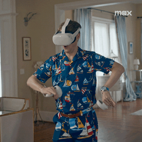 a man wearing an oculus headset is playing a video game in a living room with a max logo in the corner
