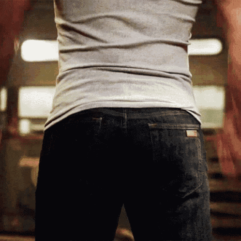a man in a grey shirt and black jeans is standing in a room