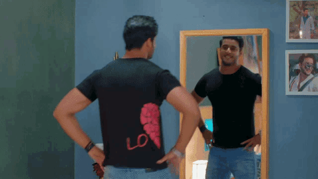 a man standing in front of a mirror wearing a black shirt that says love