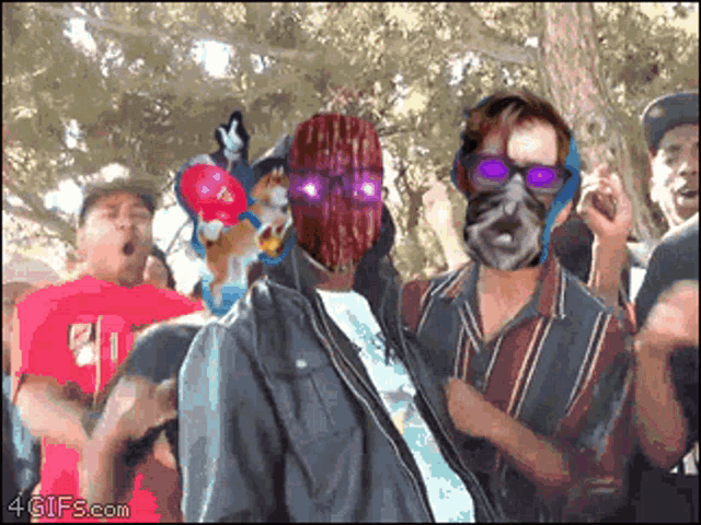 a man with a mask on his face is surrounded by a crowd of people and the website 4gifs.com is displayed