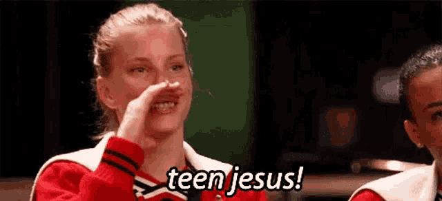 a cheerleader is covering her nose with her hand while another cheerleader says teen jesus .