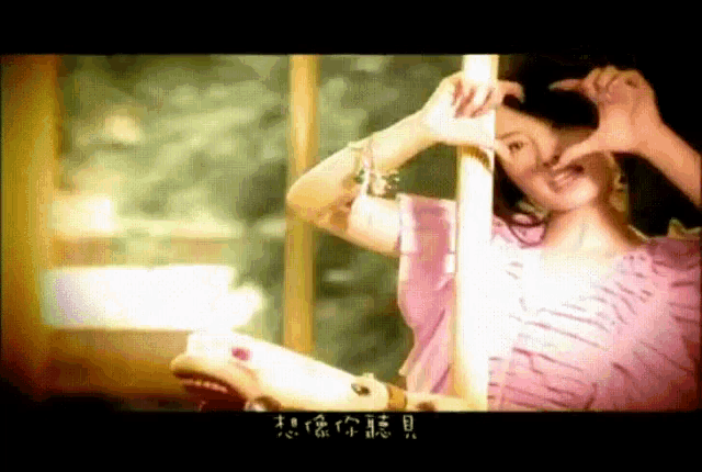 a woman making a heart shape with her hands in front of her face