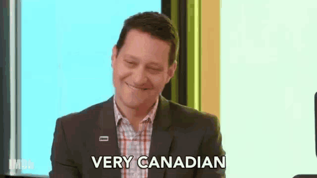 a man in a suit and tie is smiling and saying `` very canadian '' .