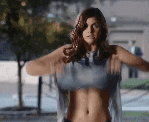 a woman is taking off her shirt and standing in front of a pool .